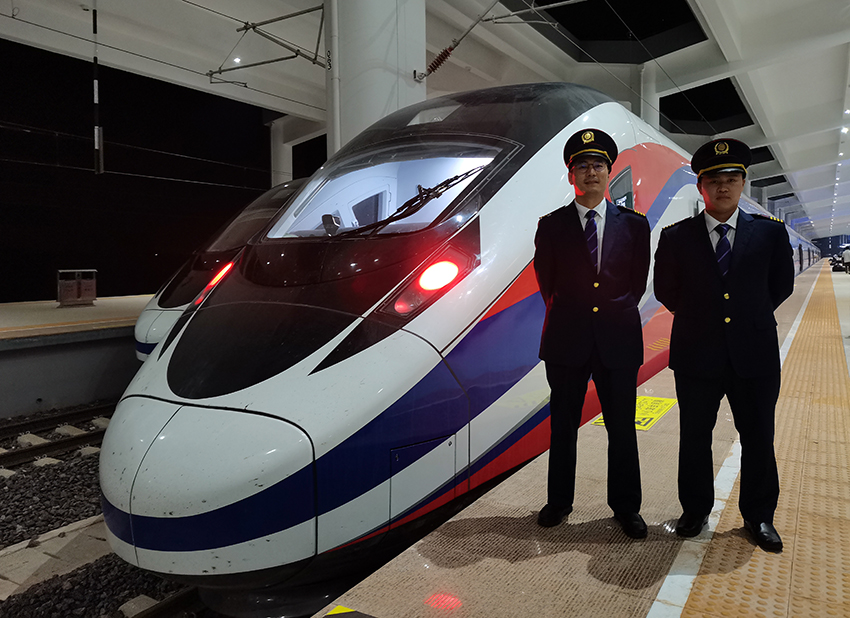 劉銀能（右一）與中國(guó)師父鄔俊鴻在動(dòng)車組前合影。受訪者供圖
